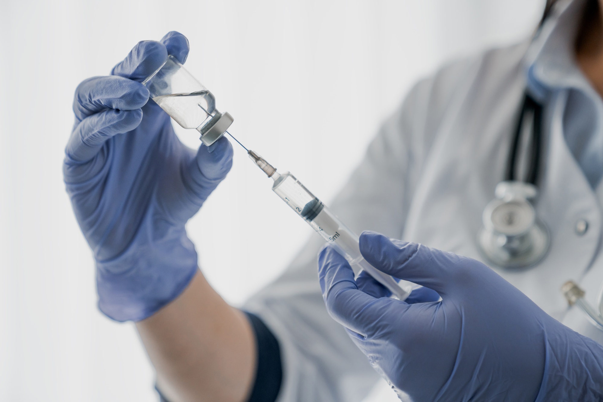 Medication nurse wearing protective gloves get a needle ready for an injection