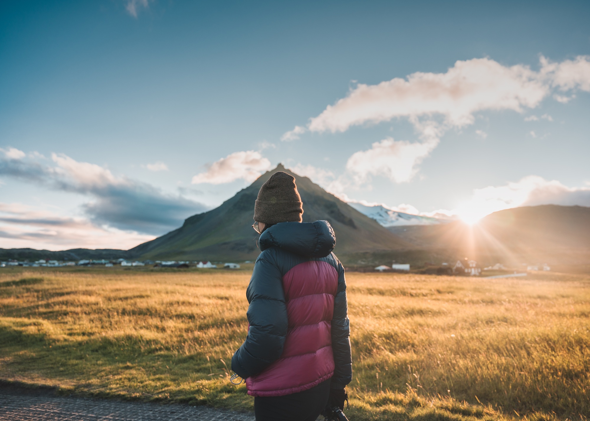 Woman in winter jacket walking through Stapafell mountain and sunlight shining in the sunset